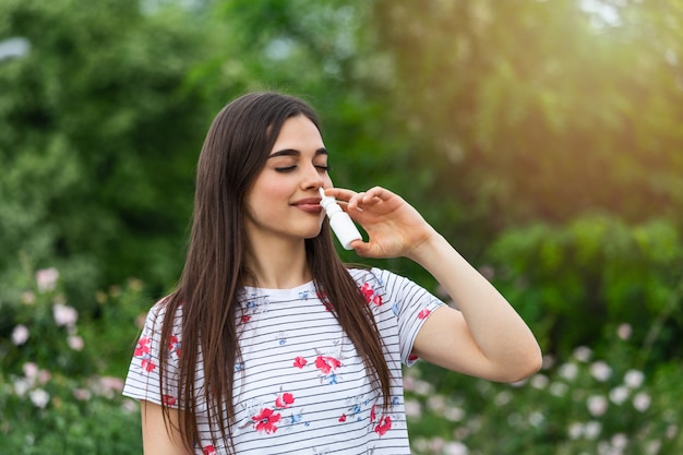 Jovem mulher usando spray nasal para suas alergias ao pólen e à grama