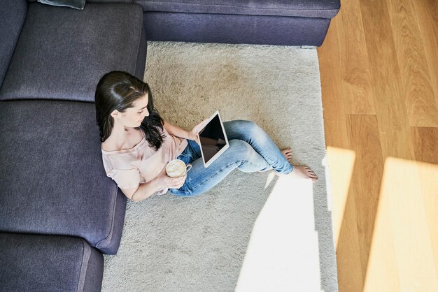 Jovem mulher usando tablet em casa na sala de estar