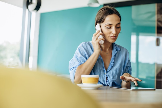 Jovem mulher usando tablet em um café e bebendo café