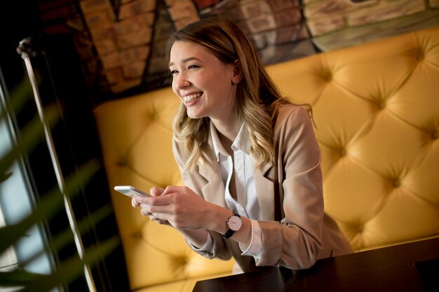 Jovem mulher usando telefone celular no café