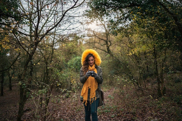 Foto jovem mulher usando uma câmera para tirar foto na floresta.