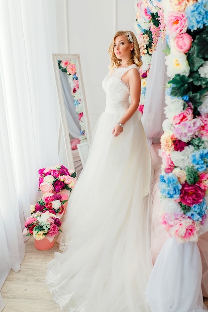 Jovem mulher usando vestido de noiva posando no quarto decorado com flores