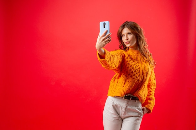 Foto jovem mulher vermelha tirando fotos de si mesma com o celular