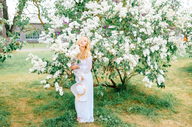 Jovem mulher vestida de branco desfrutando no parque florescendo