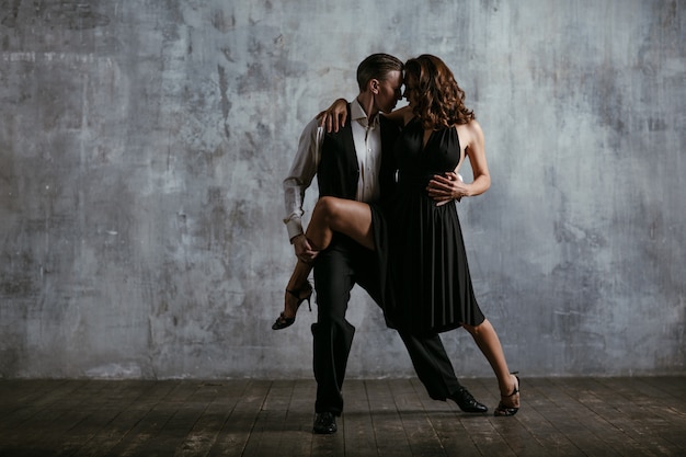 Jovem mulher vestida de preto e homem dança tango