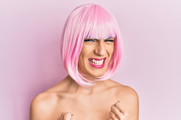 Foto jovem mulher vestindo maquiagem usando peruca rosa animada para o sucesso com os braços levantados e os olhos fechados comemorando a vitória sorrindo. conceito de vencedor.
