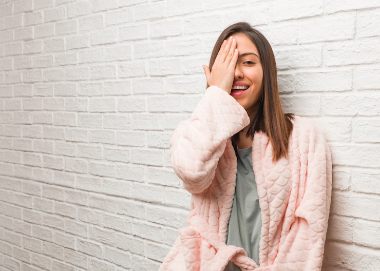 Foto jovem mulher vestindo pijama gritando feliz e cobrindo o rosto com a mão