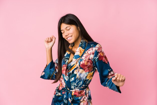 Jovem mulher vestindo um pijama de quimono dançando e se divertindo.