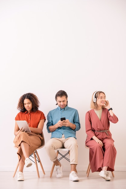 Jovem multiétnico e mulher interagindo nas redes sociais usando gadgets enquanto uma garota positiva ouve música em fones de ouvido
