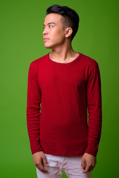 Jovem multiétnico vestindo um suéter vermelho contra um fundo verde