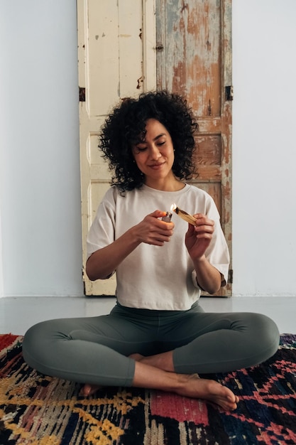 Jovem multirracial iluminando palo santo em casa se prepara para meditar espiritualidade vertical