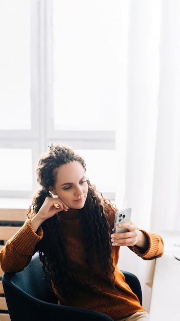 Jovem multitarefa usando smartphone e laptop para trabalho remoto e e-learning em casa