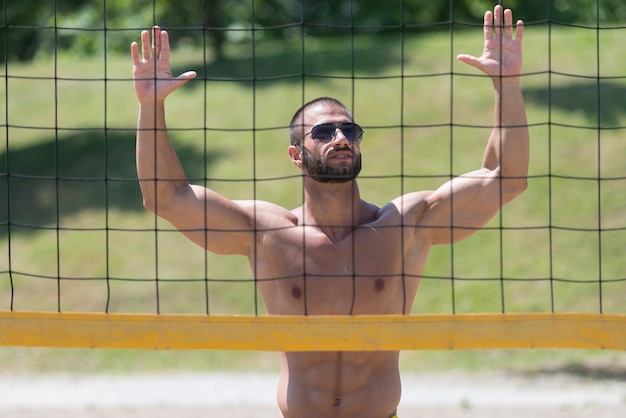 Jovem musculoso jogando vôlei de praia mergulhando depois da bola