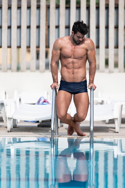 Jovem musculoso na piscina ao ar livre