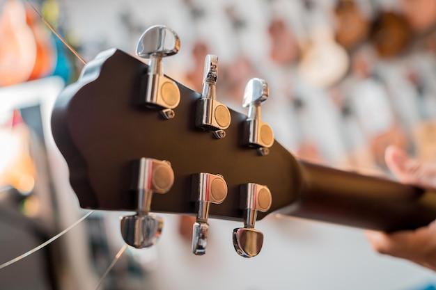 Jovem músico afinando uma guitarra clássica em uma loja de guitarra