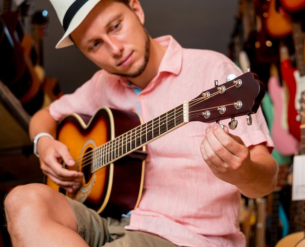 Jovem músico afinando uma guitarra clássica em uma loja de guitarras