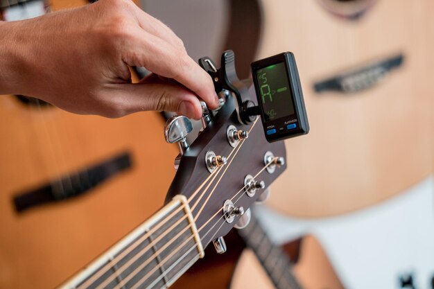 Jovem músico afinando uma guitarra clássica em uma loja de guitarras