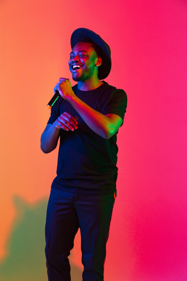 Foto jovem músico afro-americano cantando em um fundo gradiente laranjapurple estúdio