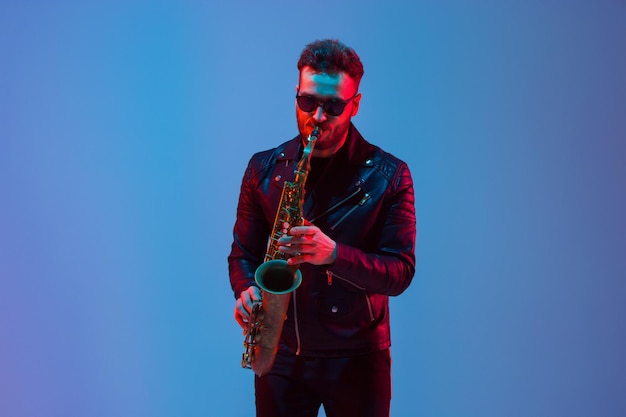 Jovem músico de jazz caucasiano tocando saxofone em luz de néon