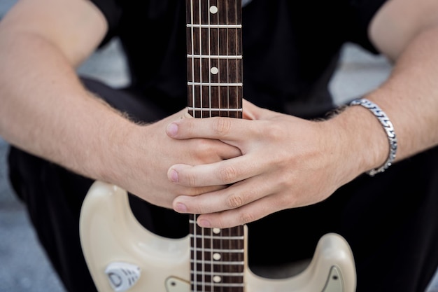 Jovem músico de rua tocando violão sentado em degraus de granito