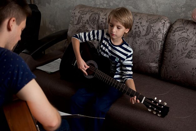 Foto jovem músico ensina aluno a tocar guitarra acústica e a tocar notas