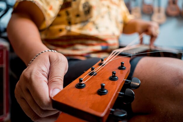 Jovem músico mudando cordas em uma guitarra clássica em uma loja de guitarras