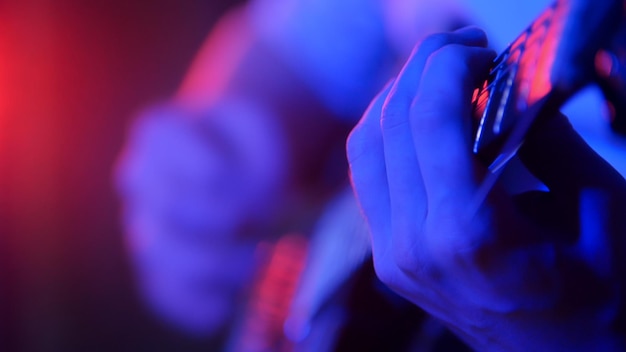 Jovem músico tocando guitarra em iluminação neon