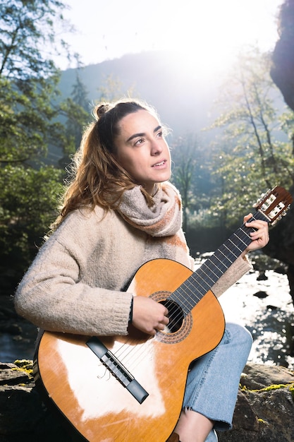 Jovem músico tocando violão na natureza