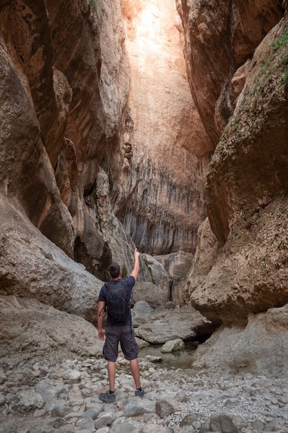 Foto jovem na entrada de um canyon, apontando a mão na frente dele. exploração de conceito, aventura