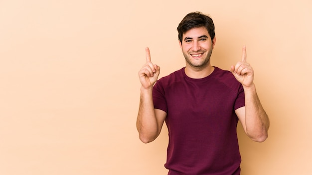 Jovem na parede bege com os dois dedos dianteiros, mostrando um espaço em branco.