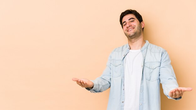 Jovem na parede bege, mostrando uma expressão de boas-vindas.