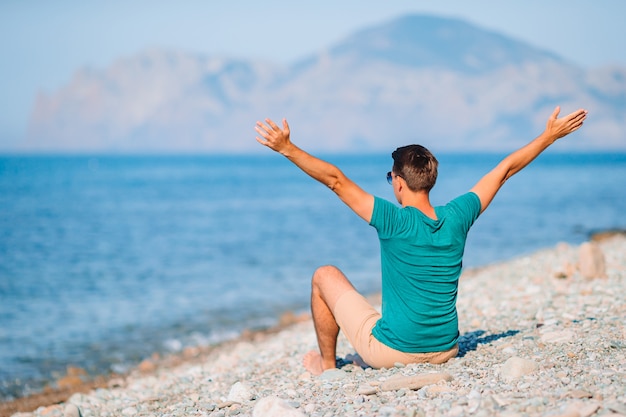 Jovem na praia relaxante com vista para as montanhas