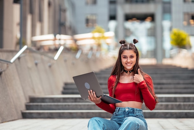 Jovem na rua usando laptop e mostra como