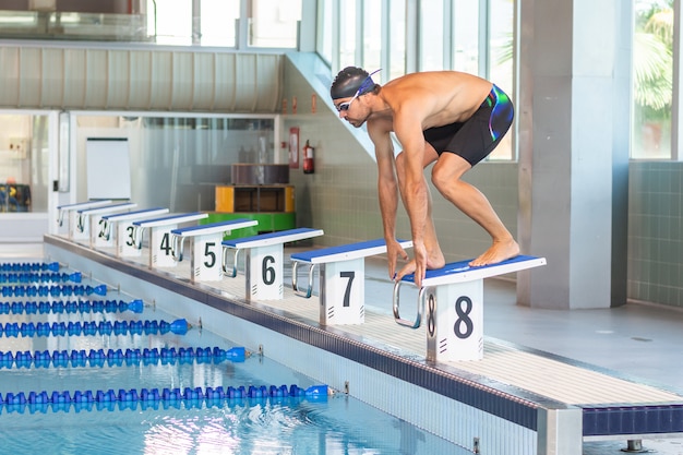 Jovem nadador preparado para pular em uma piscina olímpica