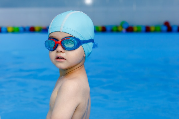 Jovem nadador profissional com boné azul pronto para nadar na água da piscina.