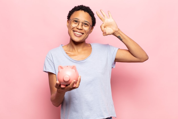 Jovem negra afro se sentindo feliz, relaxada e satisfeita, mostrando aprovação com gesto de ok, sorrindo