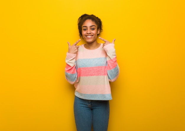 Foto jovem negra americana africano com sorrisos de olhos azuis, apontando a boca