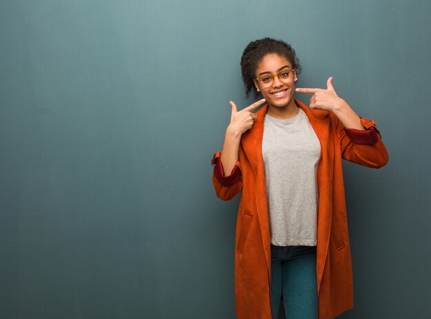 Jovem negra americana Africano com sorrisos de olhos azuis, apontando a boca