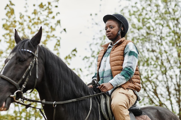 Jovem negra andando a cavalo ao ar livre