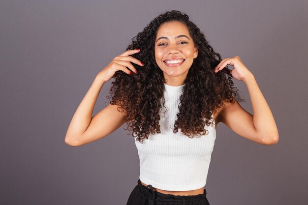 Foto jovem negra brasileira brincando com cachos de cabelo encaracolado cabelo afro abrindo o cabelo
