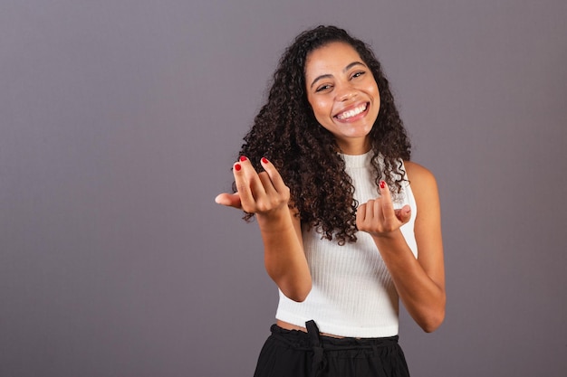 Jovem negra brasileira chamando com as mãos convidando para vir