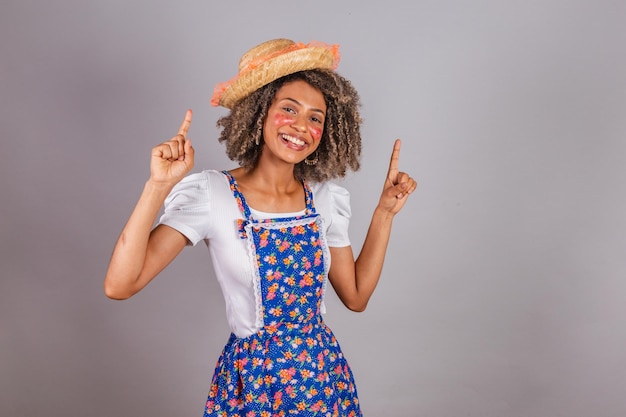 Jovem negra brasileira com roupas country vestida para a Festa Junina Saint John's festival dançando festa