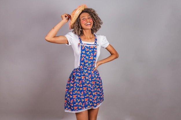 Jovem negra brasileira com roupas country vestida para a Festa Junina São João em pose para foto