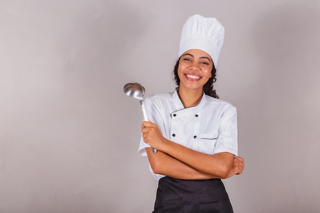 Jovem negra brasileira cozinheira segurando concha de cozinha para preparar caldos e sopas