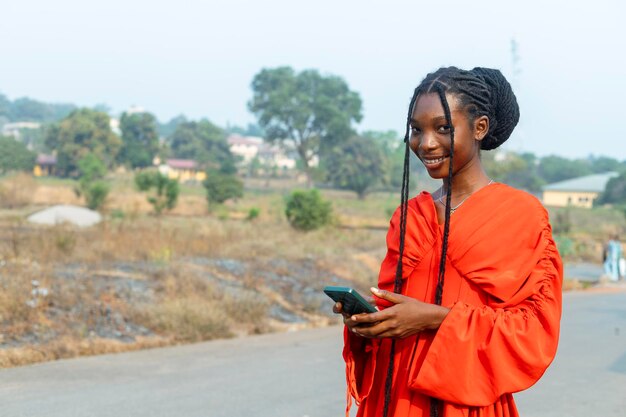 jovem negra feliz segurando um telefone celular e sorrindo olhando para a câmera