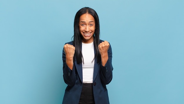 Jovem negra gritando triunfantemente, rindo e se sentindo feliz e animada ao comemorar o sucesso. conceito de negócios