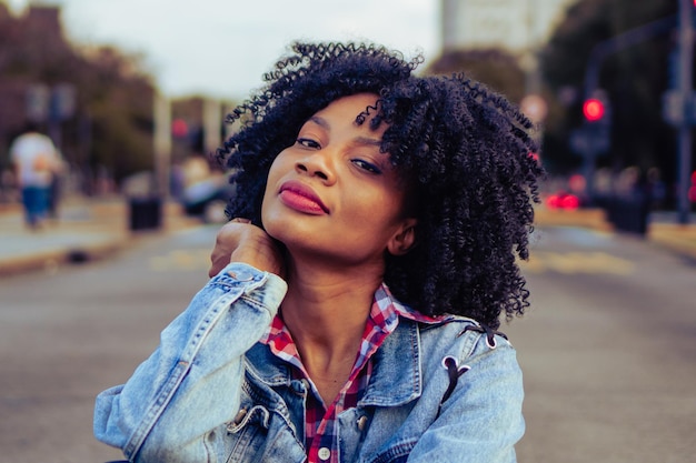 Jovem negra haitiana com cabelo afro olha para a câmera com um visual urbano