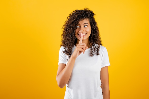 Jovem negra mostrando gesto silencioso isolado sobre amarelo