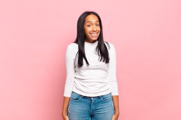 Jovem negra parecendo feliz e boba com um sorriso largo, divertido e maluco e olhos bem abertos