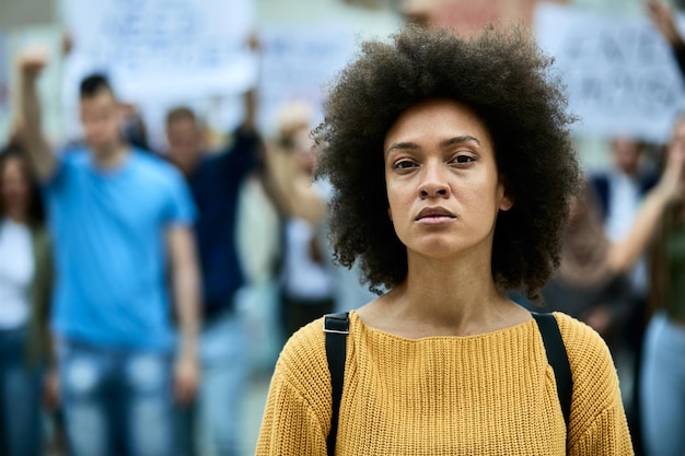 Jovem negra participando de manifestações antirracismo e olhando para a câmera